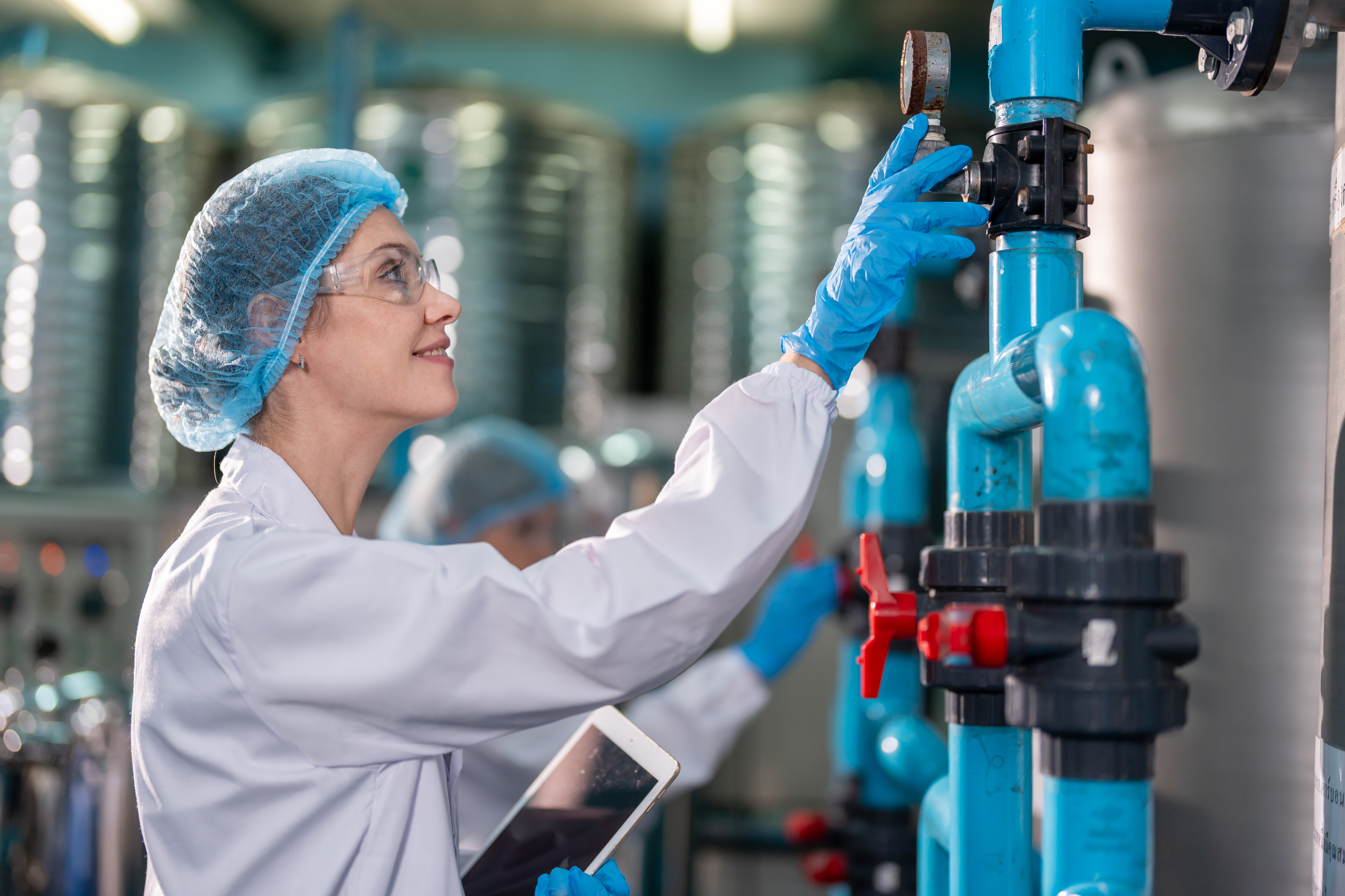 Ingeniera revisando sistema de filtración industrial con tuberías azules